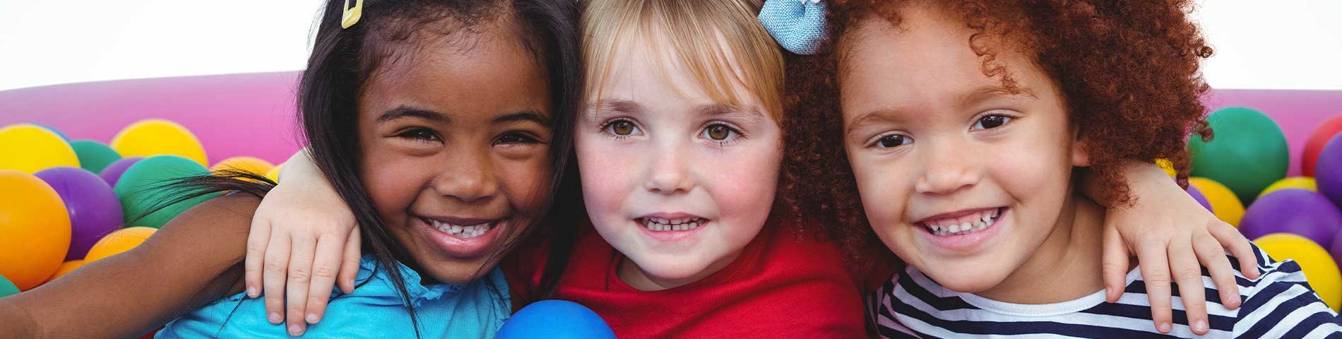 3 children sitting in a ball pit.