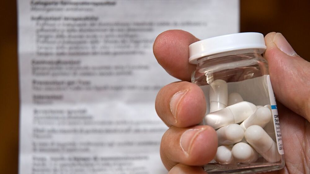 A hand holding a glass bottle prescription opioids.