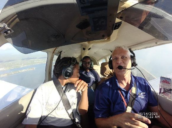 A close up of three individuals in a cockpit of a flying plane.