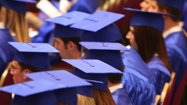 A view of graduates in blue caps and gowns from the side.